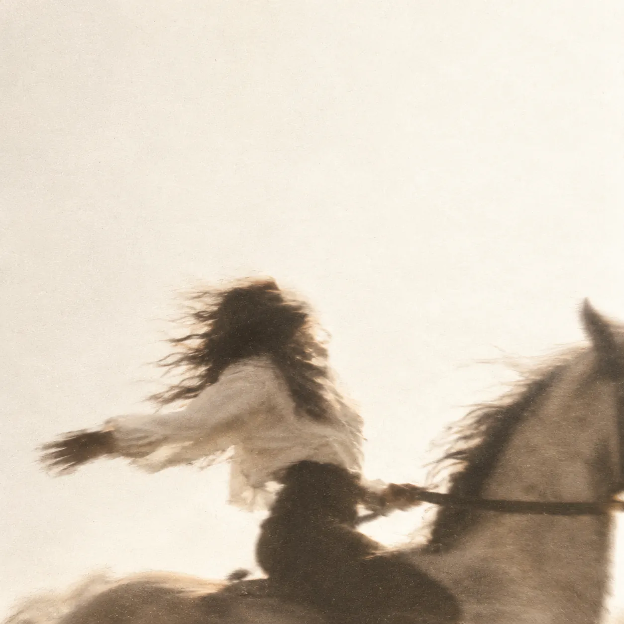 A rider on a grey, arms open against a pale sky